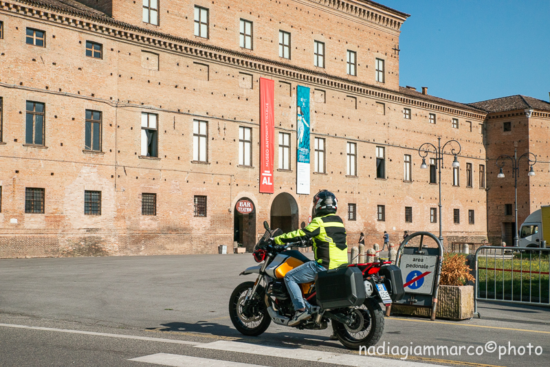 A bordo della Moto Guzzi V85TT, sullo sfondo Palazzo Bentivoglio a Gualtieri RE, sede del “Centro Studi Antonio Ligabue”
