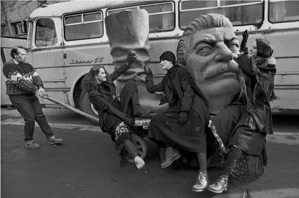 Ferdinando Scianna, Budapest, Ungheria, 1990. Tre allegre ragazze accompagnano Josip Stalin alla pattumiera della storia, 1990, 43×49 cm, ©Ferdinando Scianna